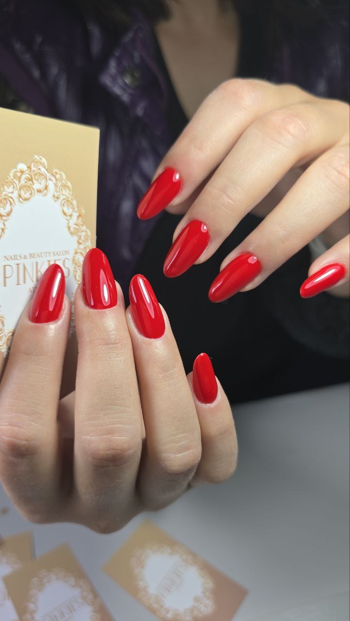 Κόκκινα αμυγδαλωτά νύχια που κρατούν την κάρτα του Pinkies